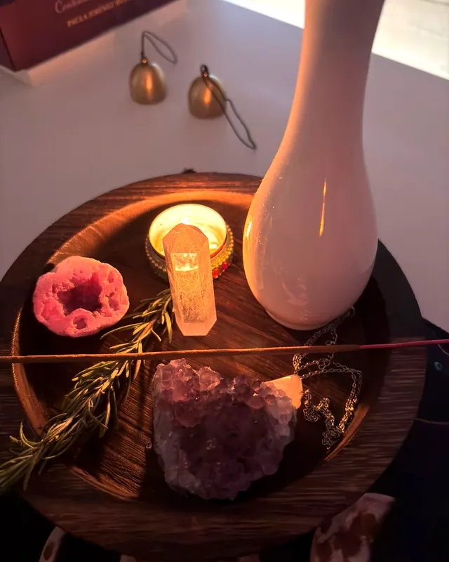 Vela encendida, cuarzo, geoda y amatista sobre una bandeja de madera
