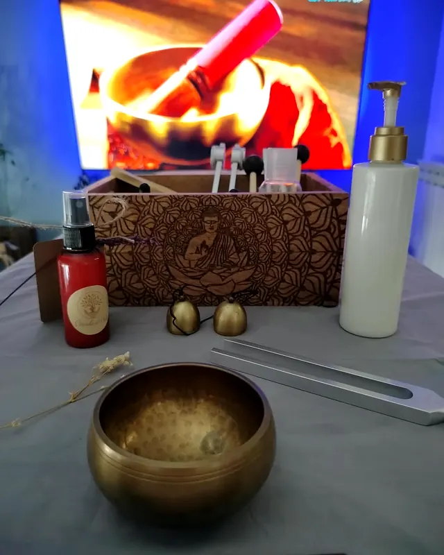 Un cuenco tibetano, campanillas y aceites junto a la camilla